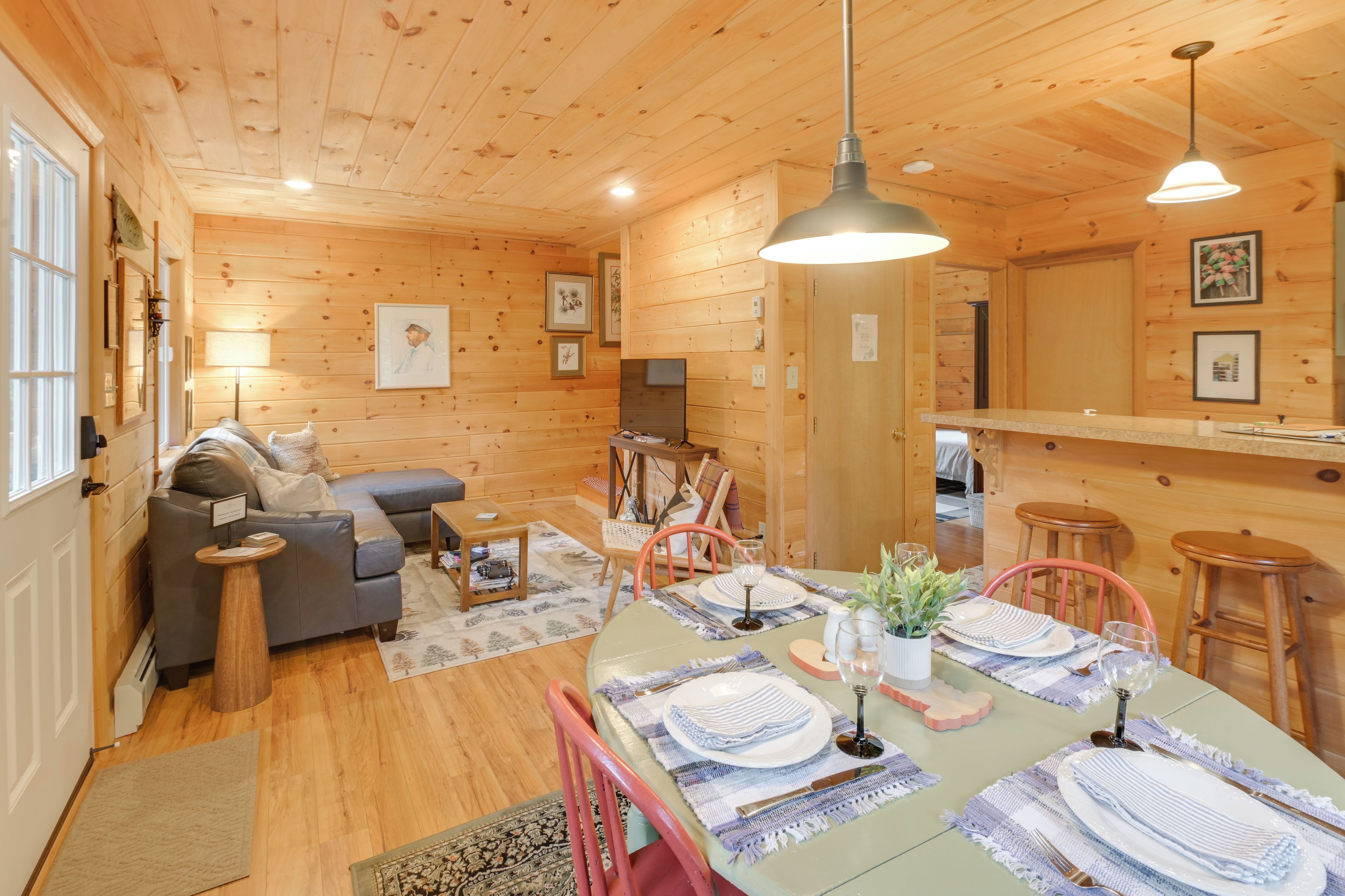 L’intérieur chaleureux d’un chalet en bois comprend un coin repas aménagé pour quatre personnes, un canapé et un téléviseur dans le salon.