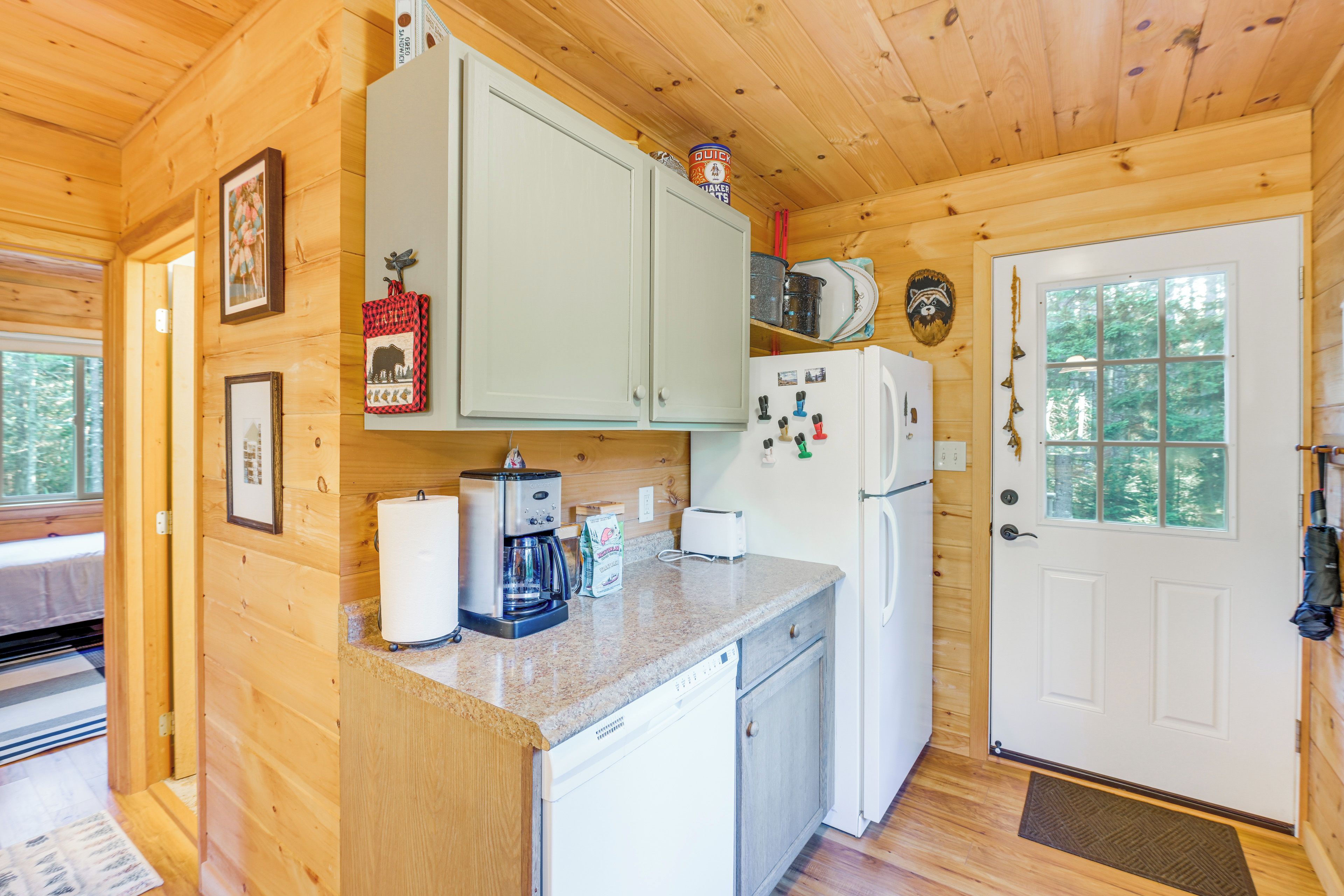 A compact kitchen with wooden cabinets, a refrigerator, a coffee maker, and a microwave.