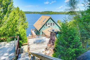 Una casa verde con terraza y vistas a un lago.