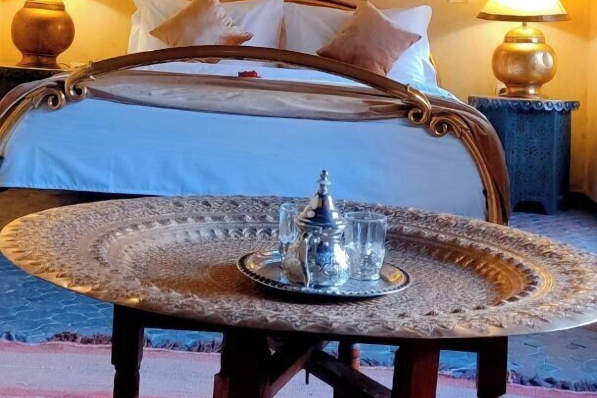 A room with a bed, two bedside lamps, a table with a tray, and a patterned carpet.