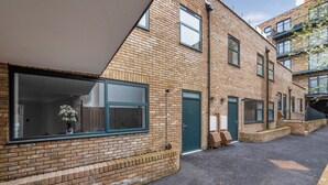 A modern brick building with large windows and a green door. - Cosy Modern Townhouse, 5mins to Tube, 02, Excel (London)