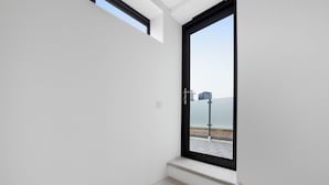 A staircase leading to a door with a view of a beach and a building in the distance. - Cosy Modern Townhouse, 5mins to Tube, 02, Excel (London)