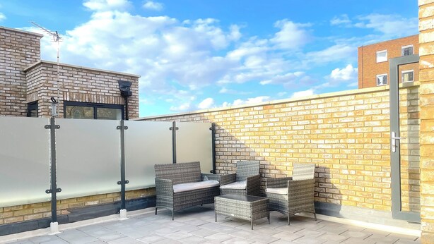 A rooftop patio with wicker furniture, a metal railing, and a brick wall. - Cosy Modern Townhouse, 5mins to Tube, 02, Excel (London)