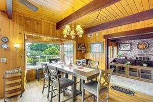 A wooden interior with a dining area, kitchen, and a brick fireplace.
