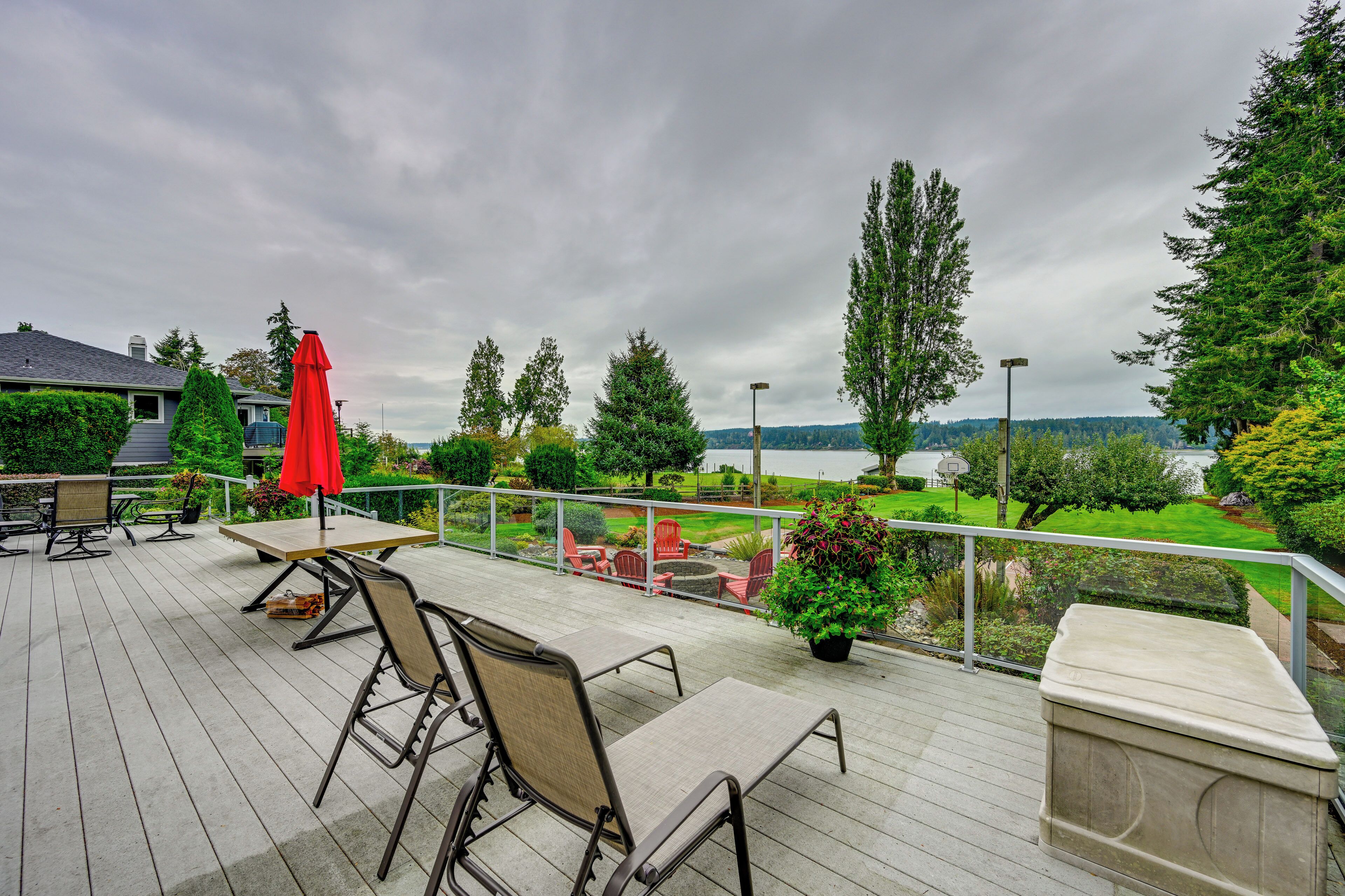 A deck with outdoor seating, a view of a lake, and surrounding greenery.