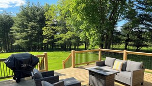 A deck with wicker furniture, a grill, and a view of a grassy area with trees. -  Quaint,newly remodeled country cabin in the heart of Bourbon Country. (Raywick)