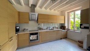 Eine moderne Küche mit Holzschränken, einem eingebauten Backofen und einem Fenster für natürliches Licht.