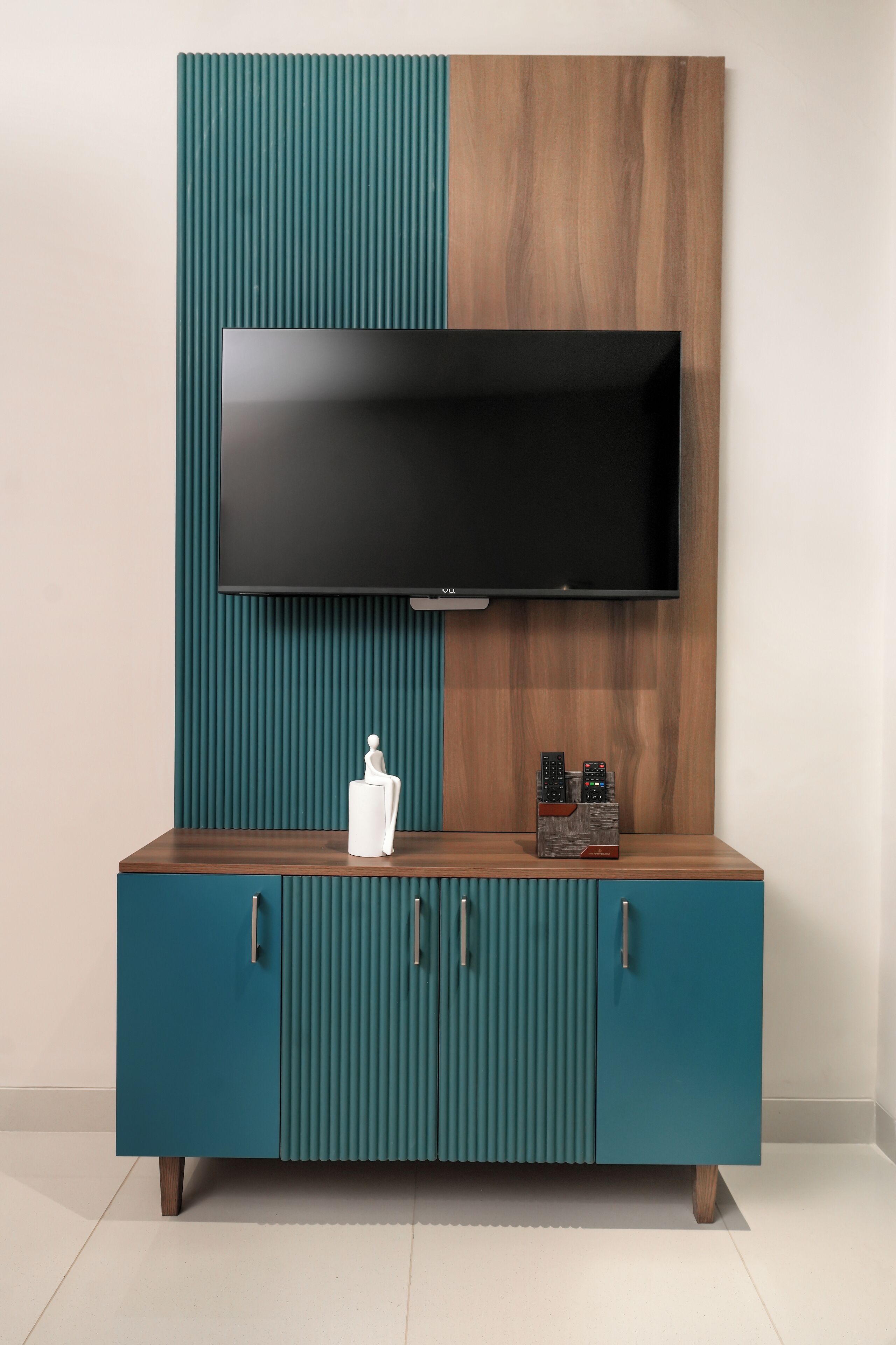 Un meuble TV aux couleurs bleu-vert et marron, sur lequel est fixé un téléviseur à écran plat.