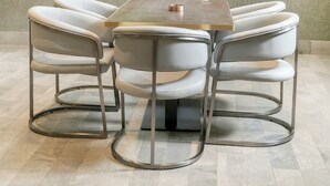 Ein moderner Essbereich mit einem runden Tisch, vier Stühlen, einem Deckenventilator und einer Wand mit Topfpflanzen.