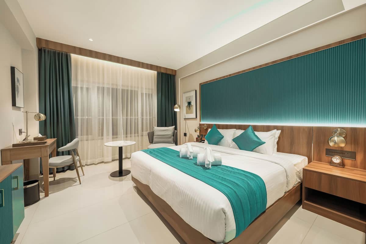 A modern hotel room with a large bed, a desk, and a chair.