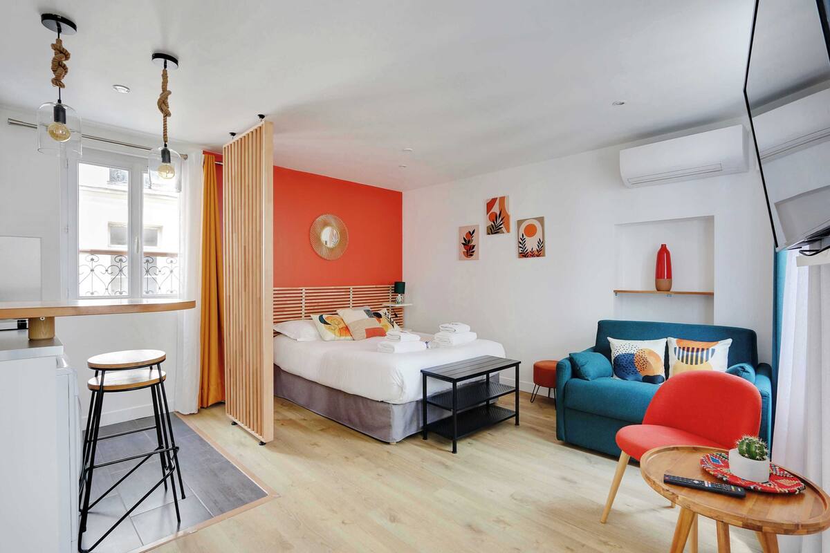 Una camera d'albergo moderna con un letto, un divano, un tavolino e un angolo bar.