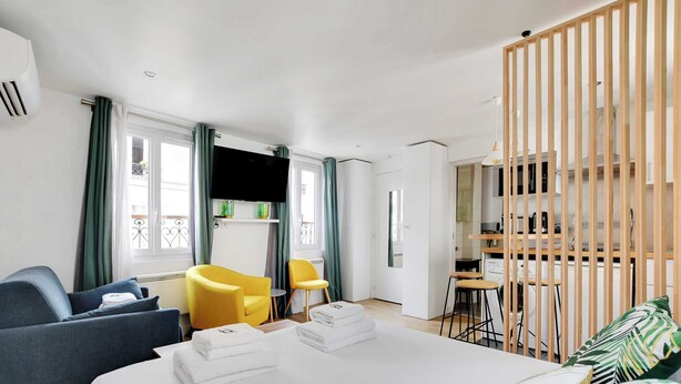 Ein modernes Hotelzimmer mit einem großen Bett, einer Couch, einem gelben Sessel und einem Schreibtisch mit einem Computer.