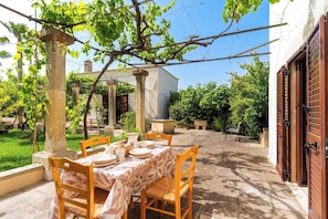An outdoor dining area with a table set for four, surrounded by stone pillars and a pergola with vines. - 4024 Casina Litta by Barbarhouse (Cutrofiano)
