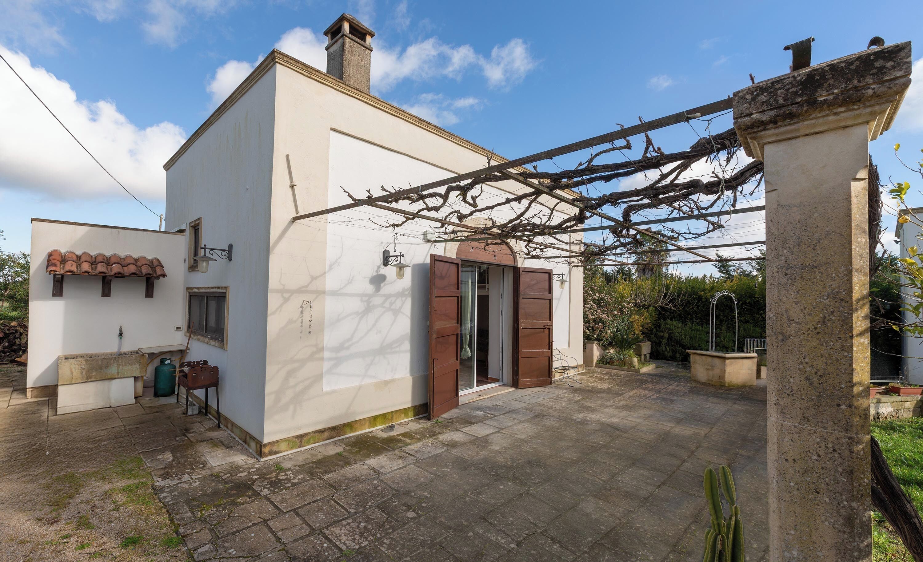 Un bâtiment blanc avec un toit en tuiles, une porte en bois et un pilier en pierre.