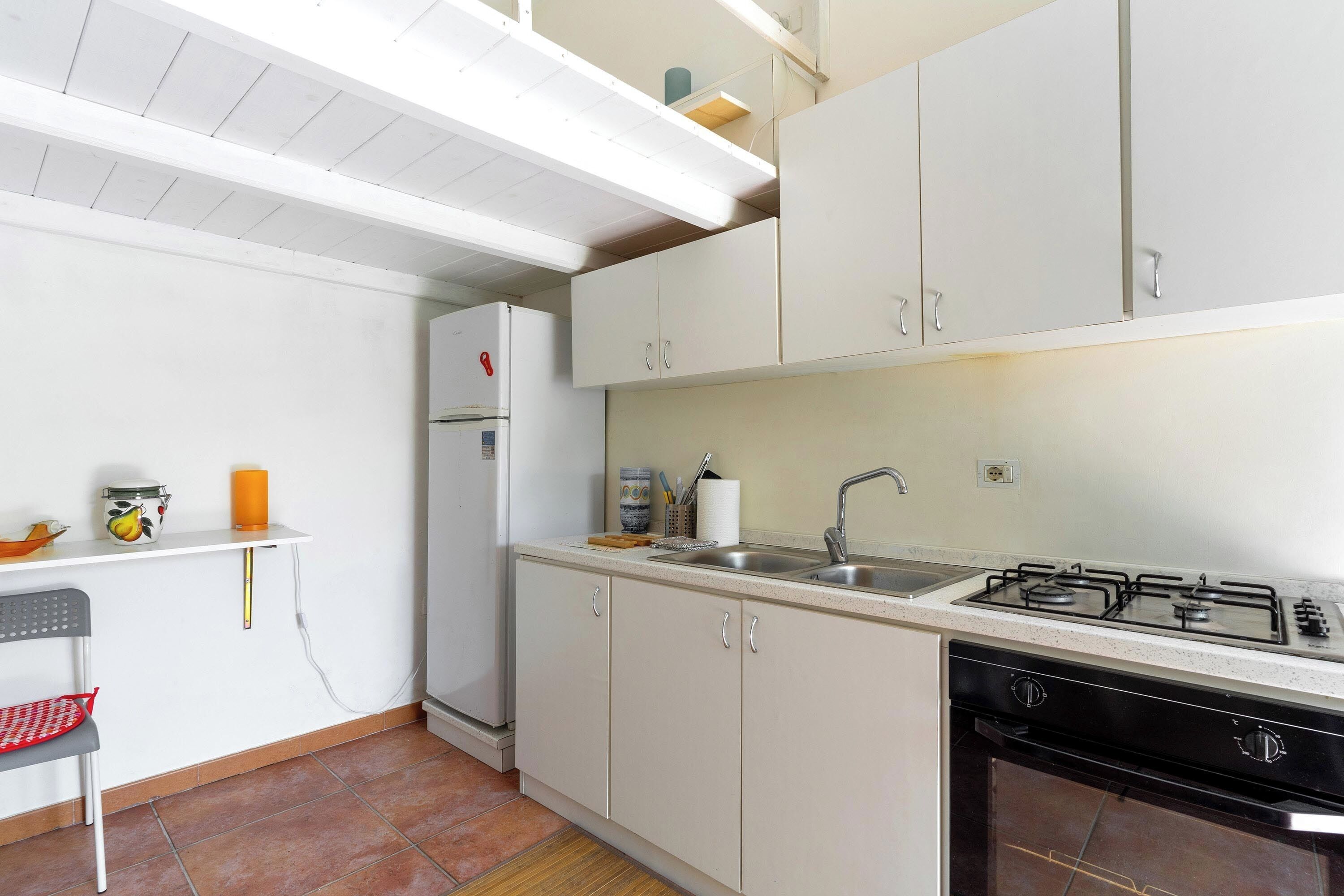 A kitchen with white cabinets, a gas stove, a sink, and a refrigerator.