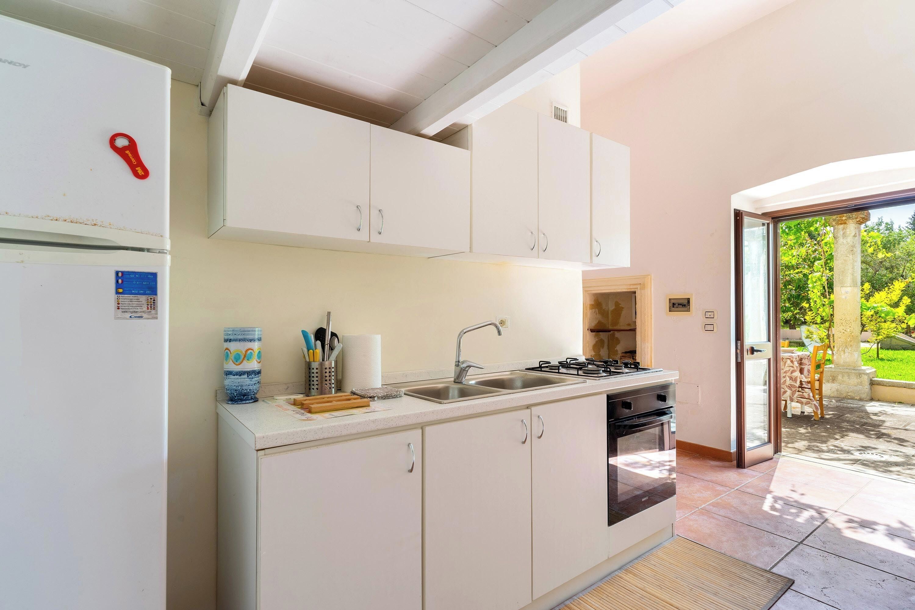 Een moderne keuken met witte kastjes, een roestvrijstalen spoelbak en een gasfornuis.
