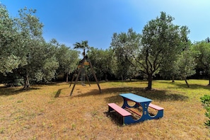 A playground with a swing set and a picnic table in a grassy area with trees. - 4024 Casina Litta by Barbarhouse (Cutrofiano)