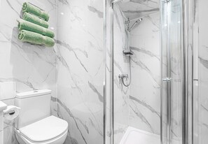 Une salle de bain avec une douche à parois de verre, des toilettes et un mur en marbre.