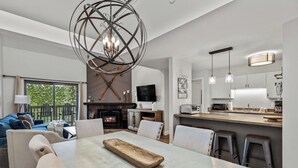 Een moderne woonkamer met een open haard, een eethoek en een keuken.