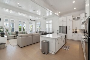 Una cocina amplia con muebles blancos, una isla central y un comedor con sofá y sillas.