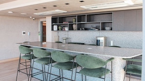 Uma cozinha moderna com bancada de granito, banquetas e prateleiras embutidas.