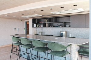 Una cocina moderna con encimera de granito, taburetes de bar y estantes empotrados.