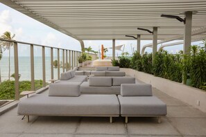 Un espacio moderno al aire libre con vistas al mar, que incluye varios sofás grises y jardineras.