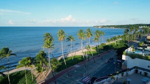 A coastal street with palm trees, a beach, and a clear view of the ocean.