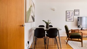 A dining area with a table, chairs, and a vase of flowers.