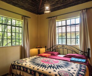 A room with a bed, a window, and a hanging light fixture.