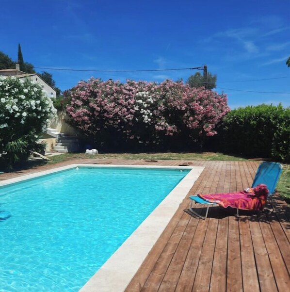 Uma piscina retangular com água azul cristalina, rodeada por um deck de madeira.