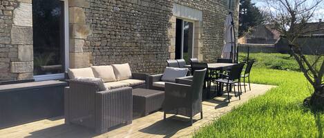 A stone building with a patio area featuring wicker furniture and a table.