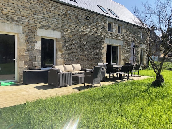 A stone building with a patio area featuring outdoor furniture and a grassy lawn.