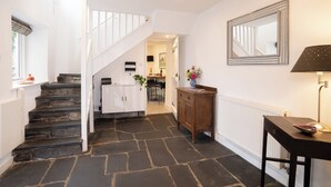 A staircase leading to a dining area with a white table and chairs, a wooden cabinet, and a mirror on the wall.