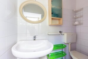 A bathroom with a white sink, a mirror, a toilet, and a green basket. - 4088 Da Nonno Claudio by Barbarhouse (Galatina)