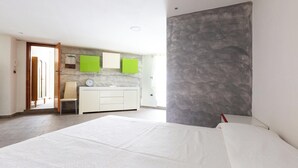A modern bedroom with a large bed, a bedside table, and a wardrobe. There is a bathroom with a mirror and a sink. - 4088 Da Nonno Claudio by Barbarhouse (Galatina)