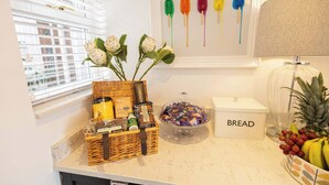 A kitchen counter with a bread box, a glass jar, a wicker basket with chocolates, and a bowl of candies.