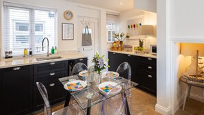 A modern kitchen with black cabinets, a glass dining table, and a central island.