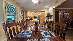 A dining room with a wooden table, chairs, and a vase of flowers. - Yellow Creek Cabin (Robbinsville)