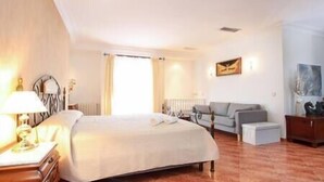 A hotel room with a bed, a sofa, a desk, and a lamp.