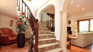 A spacious living area with a staircase, a sofa, and a potted plant.