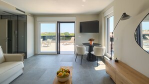 A modern living room with a sofa, a dining table with chairs, a bowl of fruit, and a TV on the wall. - Villa Loreta with pool, barbeque and sea view. (Pula)