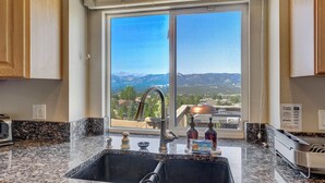 A kitchen with a large window, granite countertops, a stainless steel sink, and a view of mountains. - Air Force Academy Base with Deck and Mountain View (Colorado Springs)