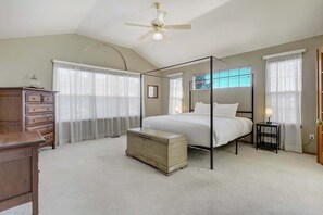 Une chambre à coucher avec un lit à baldaquin, une commode en bois, une commode à tiroirs et un ventilateur de plafond.