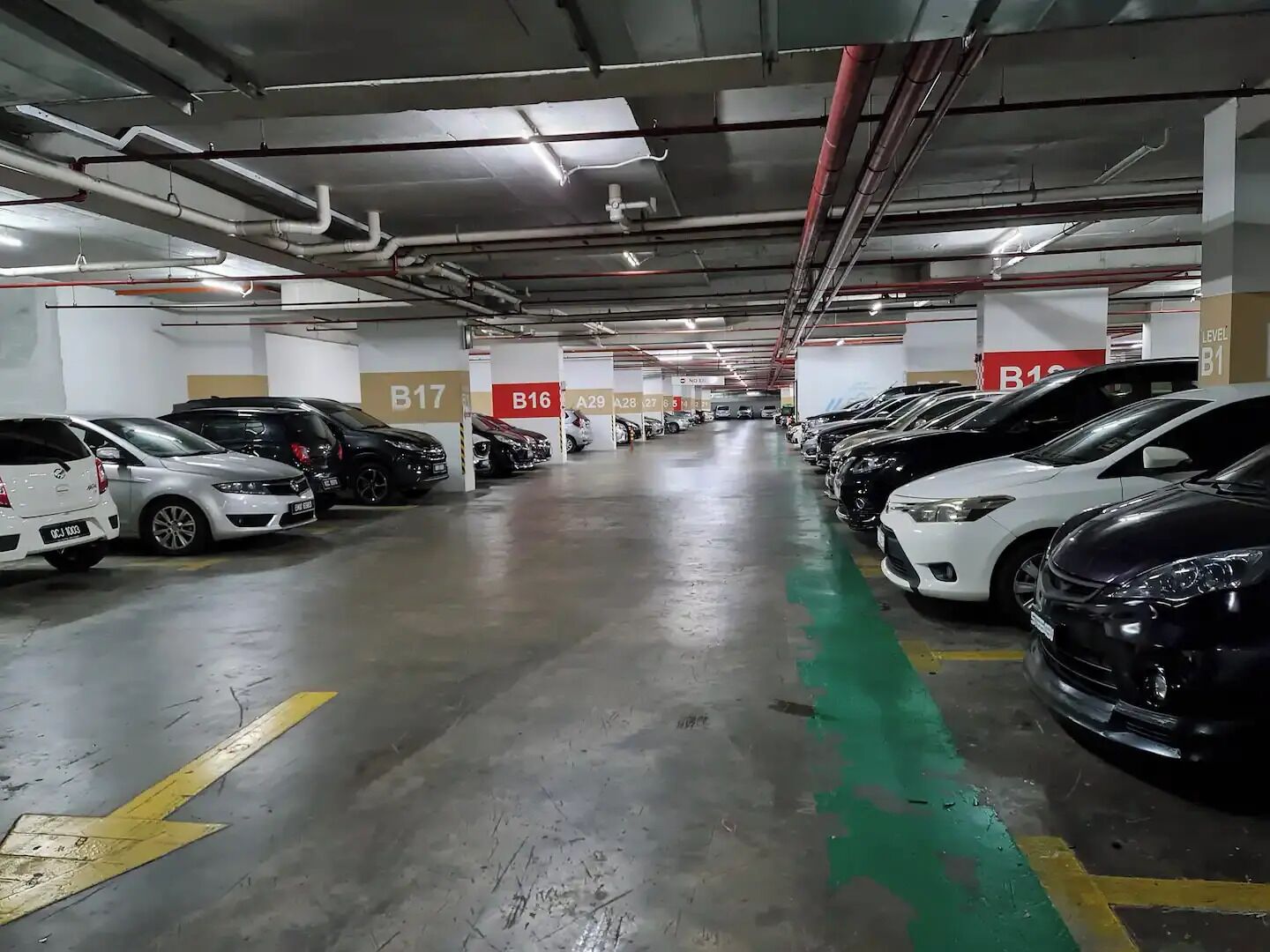 En underjordisk parkeringskælder med flere niveauer, hvor biler er parkeret i nummererede parkeringsbåse: B17, B16, A29, A28, 27, 26 og 25.