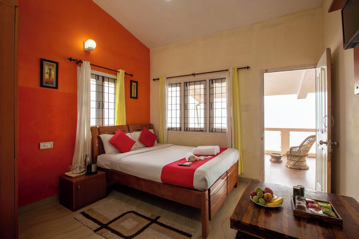 A bedroom with a bed, bedside table, and a view of the balcony.