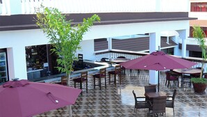 An outdoor patio area with tiled flooring, multiple tables and chairs, and potted plants. - White Peacock Resort (Mtwapa)