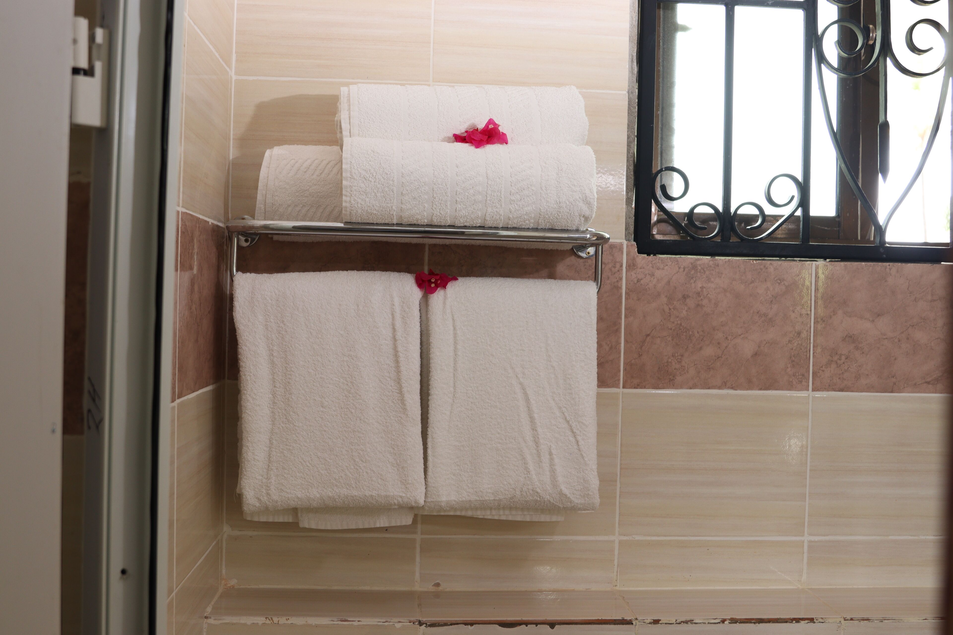 A bathroom with two white towels on a rack, one with a red flower.