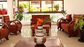 A room with a wooden table, a vase with flowers, and several wooden chairs. - White Peacock Resort (Mtwapa)