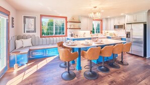 Une cuisine moderne dotée d’un îlot central, de tabourets de bar et d’un banc intégré avec espace de rangement.